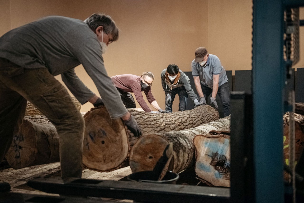 Die schweren Baumstämme werden gemeinsam im Team für die Ausstellung vorbereitet (v.l.n.r. Michael Ludorf, Naeem Ali, Aminul Islam, Manfred Schlösser). Foto: LWL/Steinweg