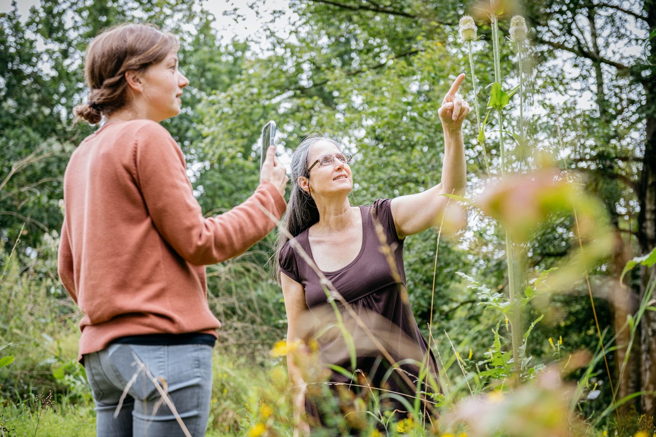 Zwei Frauen erforschen mit einem Mobiltelefon die Natur.